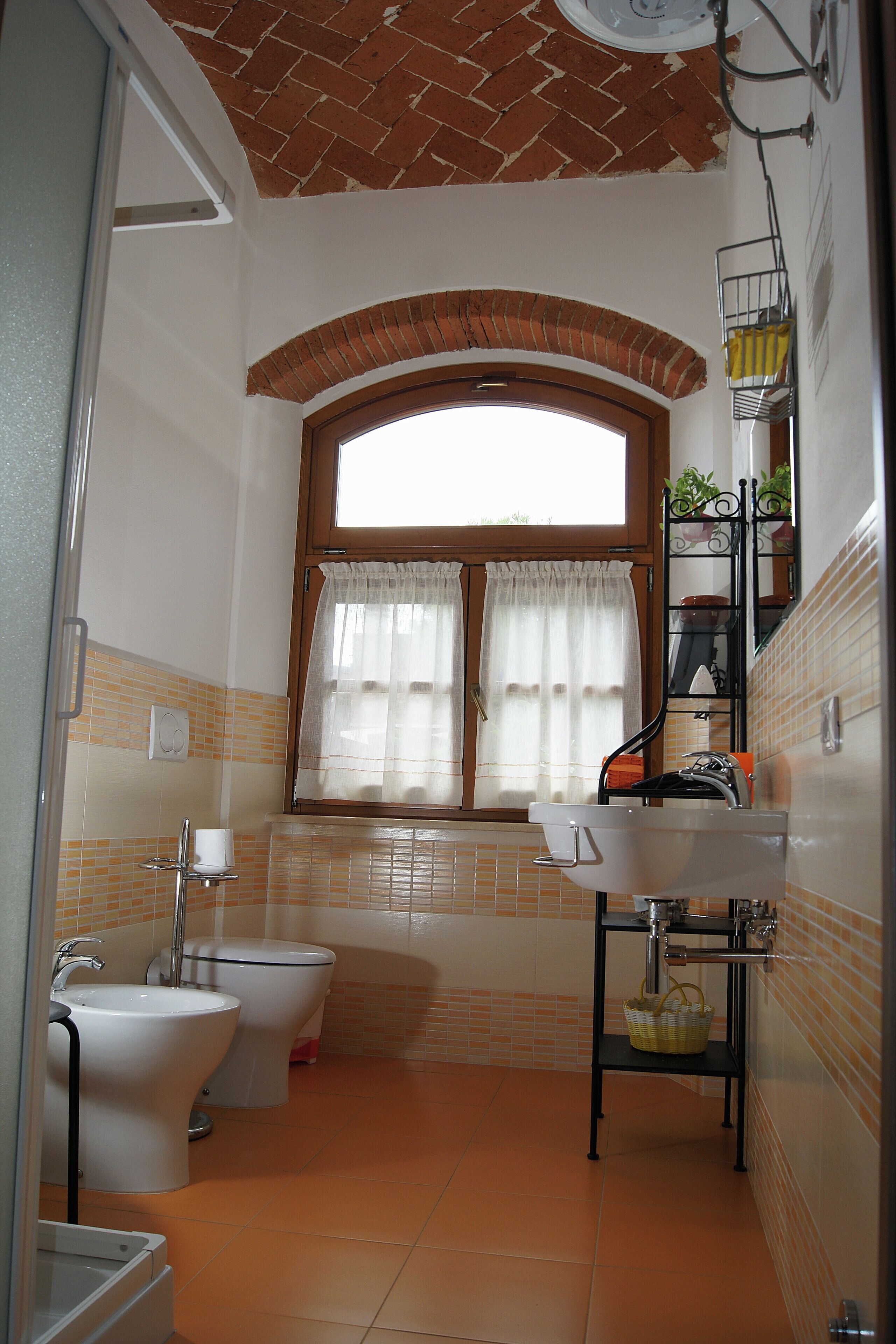 A bathroom with a window, a sink, a toilet, and a bidet.