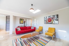 A modern living room with a red sofa, yellow armchairs, a wooden coffee table, and a colorful striped rug. - Villa Serena - 10 minutes from the beach (Bonifacio)