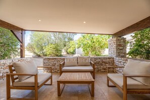 A covered outdoor seating area with stone walls and wooden furniture. - Villa Serena - 10 minutes from the beach (Bonifacio)