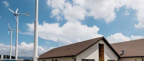 A building with a modern design, featuring a sloped roof and a gravel driveway.