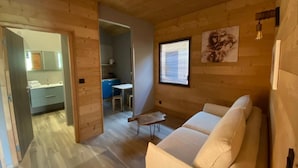 A wooden cabin interior with a sofa, a small table, and a window. - WORLD HOTEL (Saint-Vulbas)