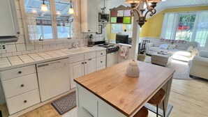 Une cuisine moderne avec des meubles blancs, un îlot central en bois et des luminaires suspendus.