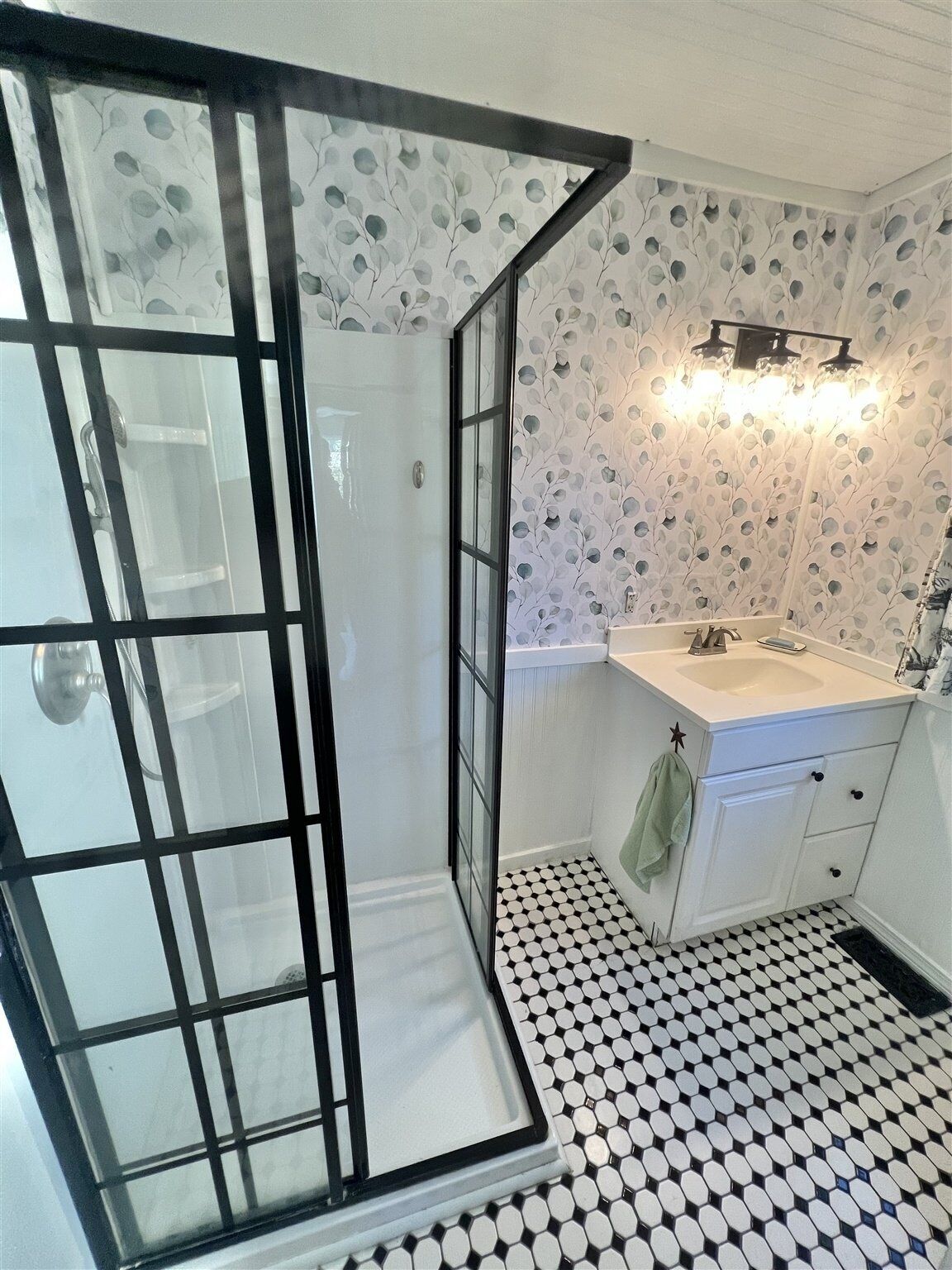 Et badeværelse med bruser, håndvask og toilet.