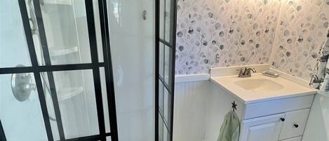 Et badeværelse med bruser, håndvask og toilet.