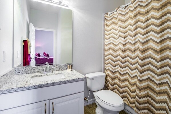A bathroom with a white sink, a toilet, and a shower curtain with a zigzag pattern. - Irish Charm 6 Bedroom Home (Kissimmee)