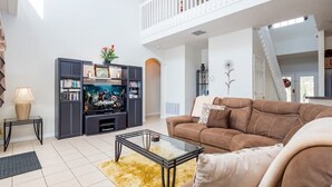 Moderni olohuone, jossa on sohva, sohvapöytä, televisio ja kirjahylly.