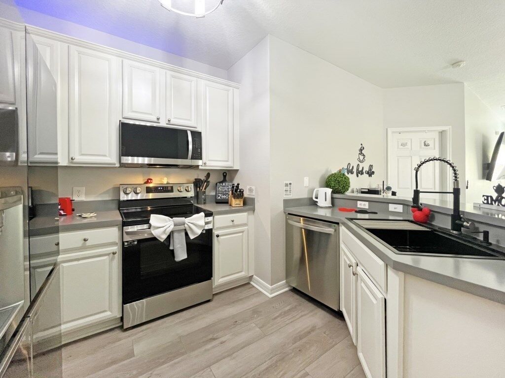 A modern kitchen with white cabinetry, stainless steel appliances, and a grey countertop.