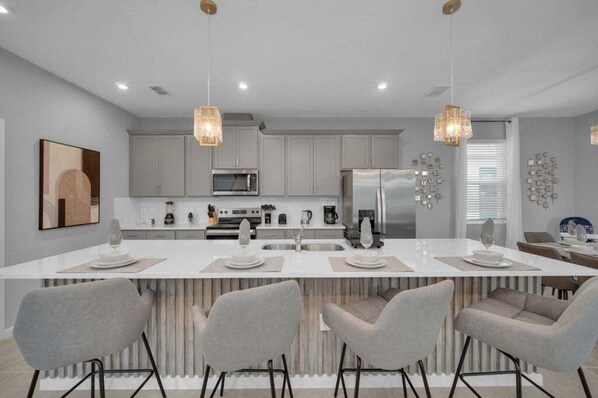 A modern kitchen with a central island, grey cabinets, stainless steel appliances, and pendant lighting. - 6 Bed 5 Bath Villa Pool&games Solara 2386salty 6 Bedroom Villa (Kissimmee)