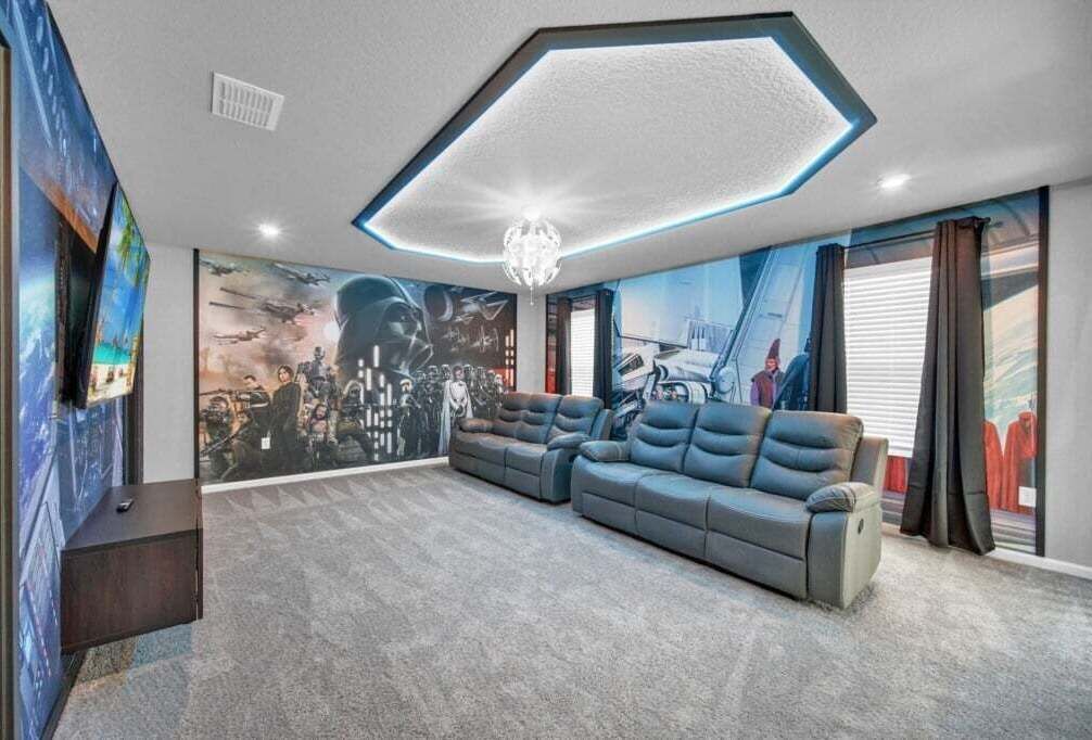 A modern living room with a sectional sofa, a large mural, and a unique ceiling design.