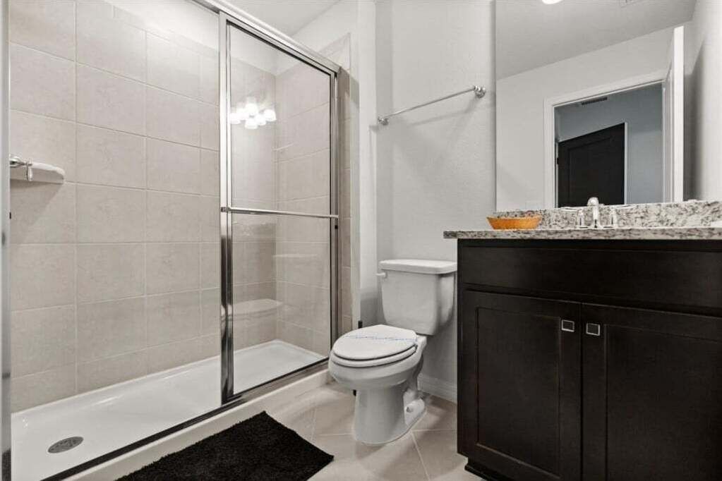 Un baño con ducha de vidrio, inodoro y armarios de madera oscura.