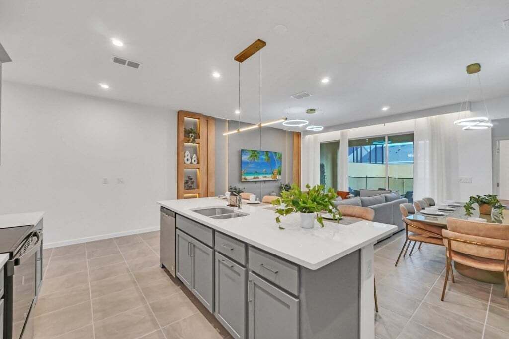 A modern kitchen with a central island, built-in appliances, and a dining area with a table and chairs.