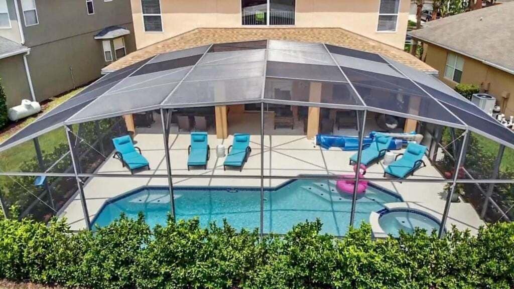 A covered outdoor swimming pool with lounge chairs and a hot tub.