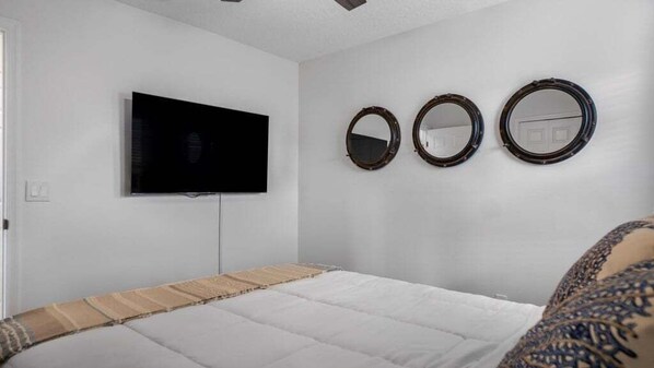 A bedroom with a bed, a television, and three wall-mounted mirrors. - Lovely 7 Bed Pool Home With Game Room-8510phd 7 Bedroom Home (Kissimmee)