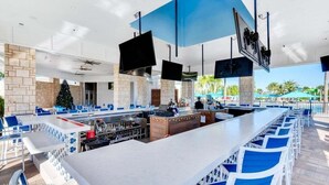 Ett modernt utomhusområde med bar, flera olika sittgrupper, en central bardisk och tv-apparater som hänger uppe.