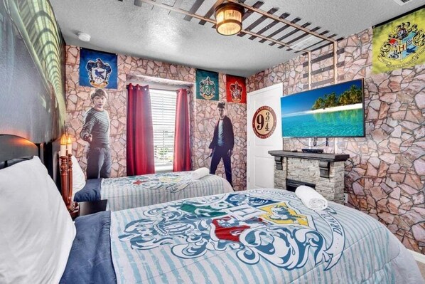 A hotel room with a stone wall, two beds with themed bedding, a television, and a fireplace. - Your Enchanted Take Me Away Townhome! 5 Bedroom Townhouse (Davenport)