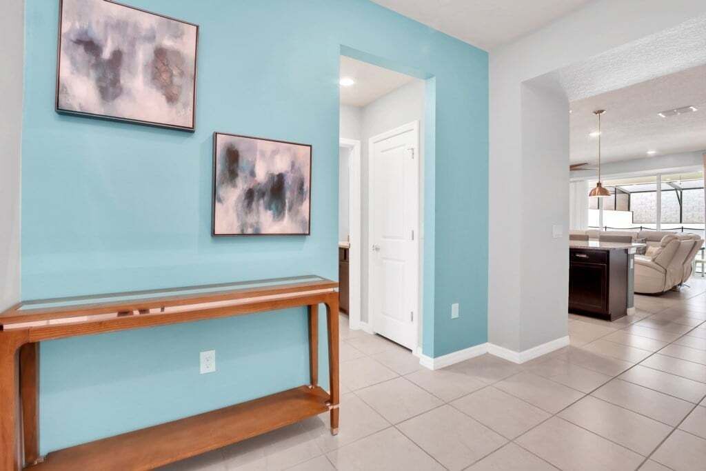 A modern living room with a light blue accent wall, a wooden console table, and abstract art.