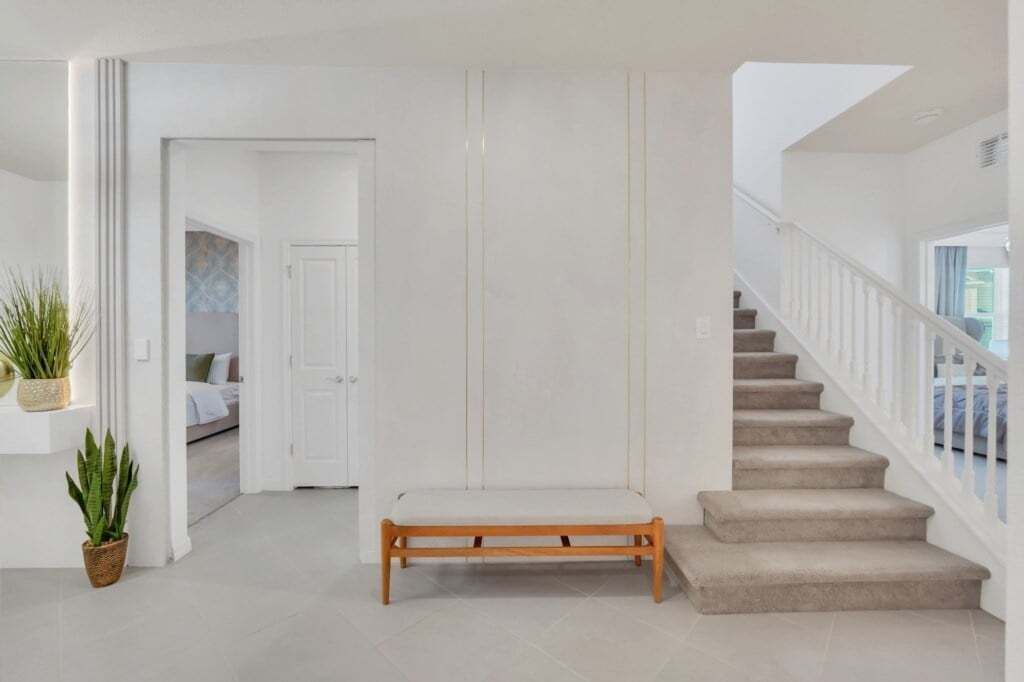 Ein geräumiger Flur mit einer hölzernen Bank, einer Treppe und einer Tür zu einem weiteren Raum.