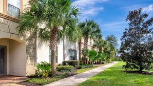 A row of modern buildings with palm trees and a well-maintained lawn. - Beautiful Tranquil Relaxing Home With Private Pool 4 Bedroom Townhouse (Kissimmee)