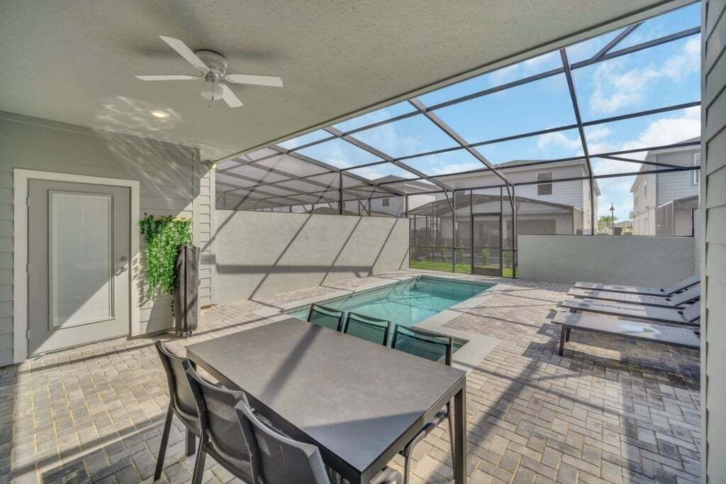 Un espacio al aire libre cubierto con piscina, asientos y ventilador de techo.