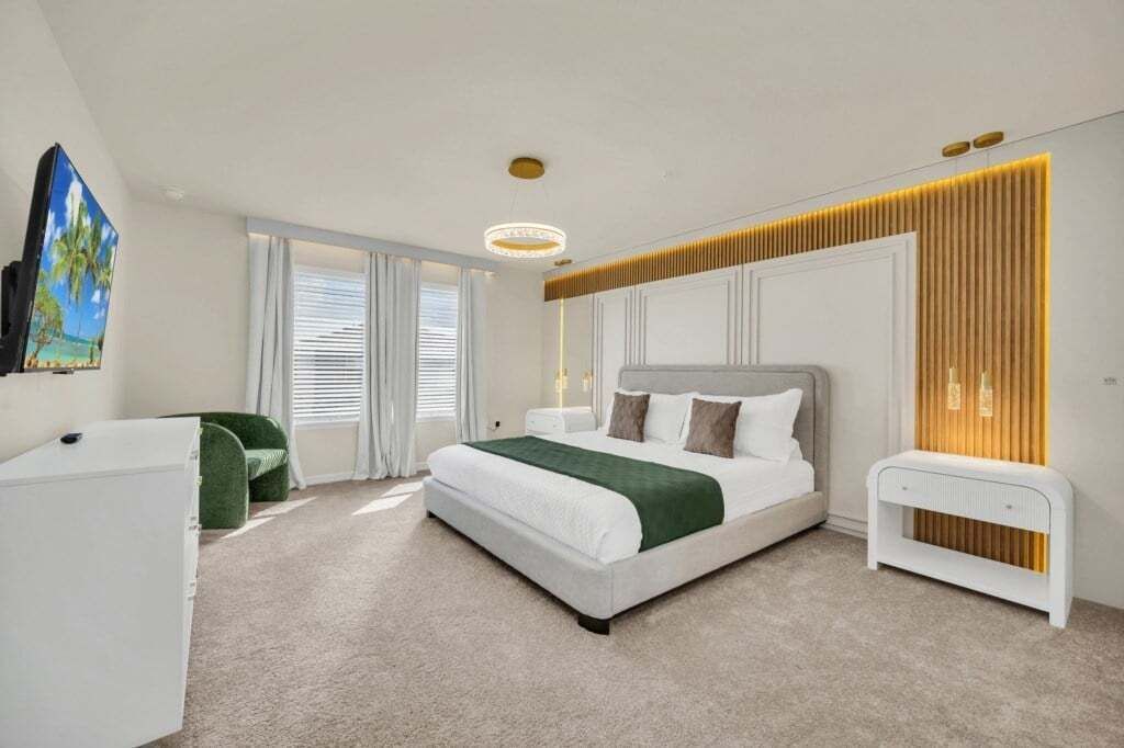 Une chambre à coucher moderne avec un grand lit, une table de chevet, un bureau et un tableau accroché au mur.