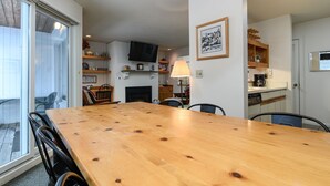 Zona pranzo con tavolo e sedie in legno, una televisione e un camino.