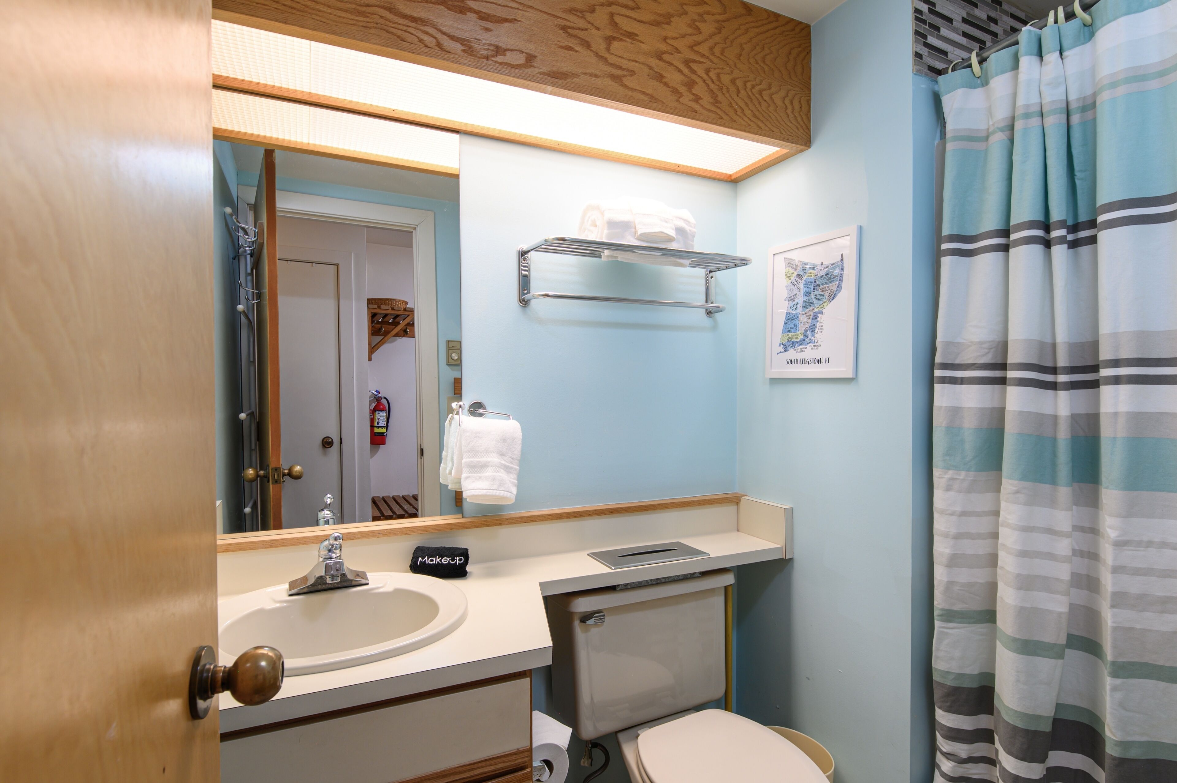 Ein Badezimmer mit Waschbecken, Spiegel, Handtuchhalter und Toilette.