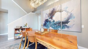 A dining area with a wooden table, chairs, and a large abstract painting on the wall. - Snowcreek V #888 3 Bedroom Condo (Mammoth Lakes)