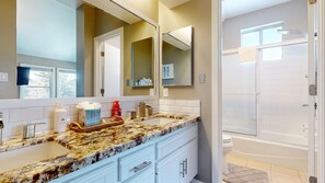 A bathroom with a granite countertop, white cabinets, a large mirror, and a shower area. - Snowcreek V #888 3 Bedroom Condo (Mammoth Lakes)