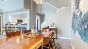 A spacious dining area with a wooden table and chairs, a kitchen in the background, and a staircase leading to an upper level. - Snowcreek V #888 3 Bedroom Condo (Mammoth Lakes)