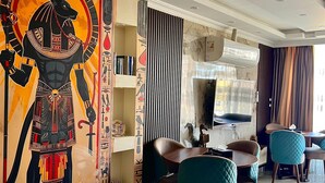 Un comedor moderno con un mural de una figura egipcia, techo con iluminación empotrada y un equipo de aire acondicionado grande.