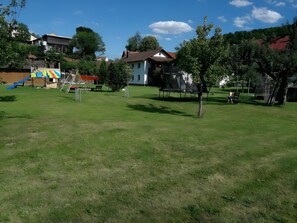 A grassy park with playground equipment, trees, and houses in the background. - Apartment '70m²' with Shared Garden, Balcony and Wi-Fi (Hayingen)