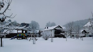 Una zona residencial con casas cubiertas de nieve y un parque infantil.