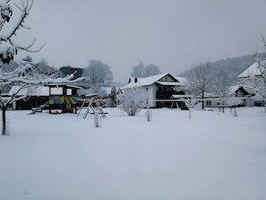 Een woonwijk met huizen onder de sneeuw en een speeltuin.