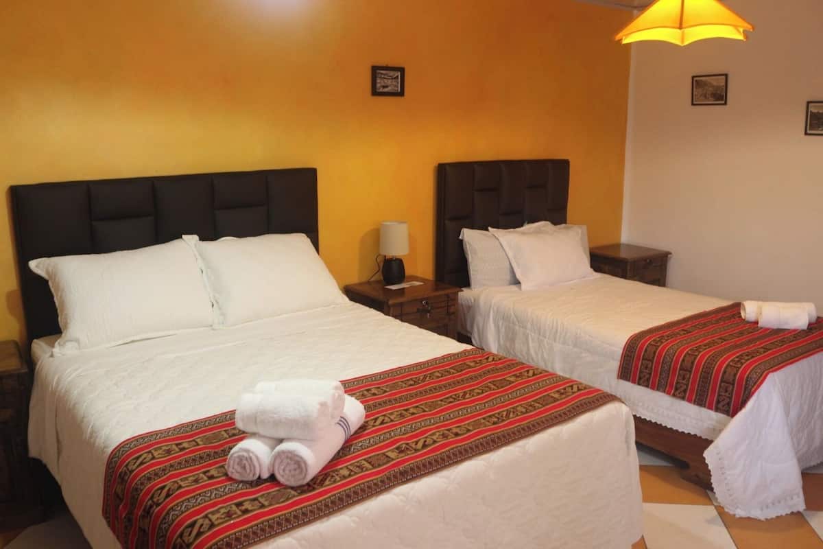 Two beds with headboards, a nightstand, a lamp, and a towel on the bed.