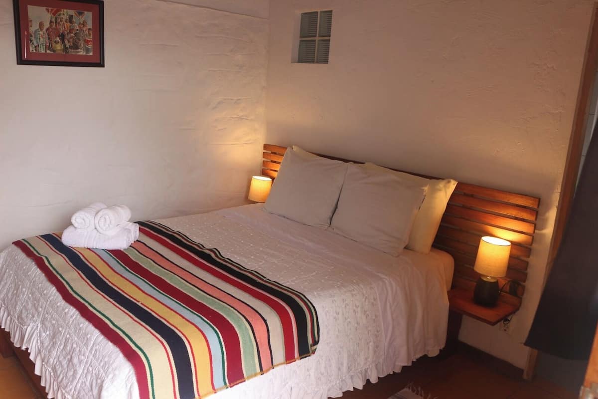 A neatly made bed with a striped blanket, white pillows, and two bedside lamps.
