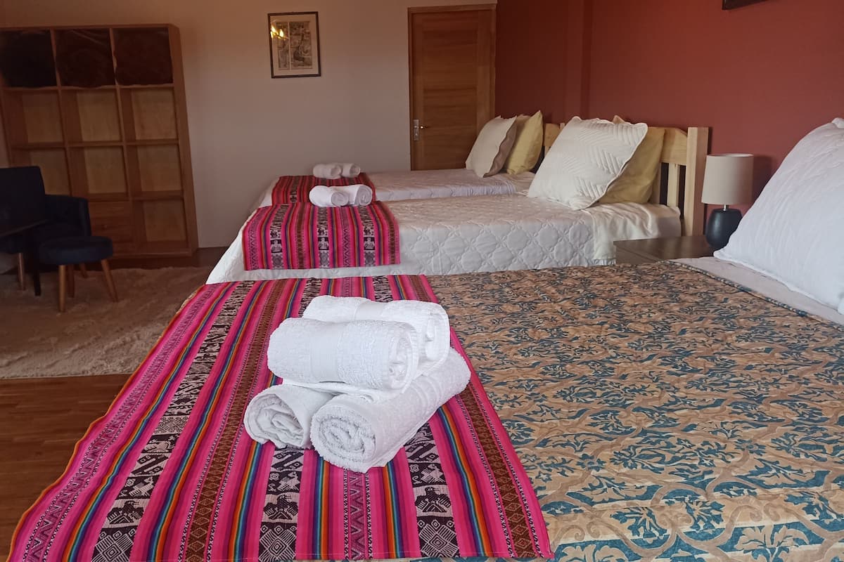 A hotel room with two beds, a desk, a chair, and a door.