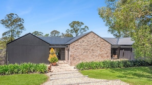 Une maison moderne avec une extension en briques, une allée pavée et une pelouse bien entretenue.