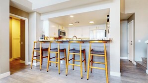 Une cuisine moderne dotée d’un îlot central, de quatre tabourets de bar et d’un four à micro-ondes.