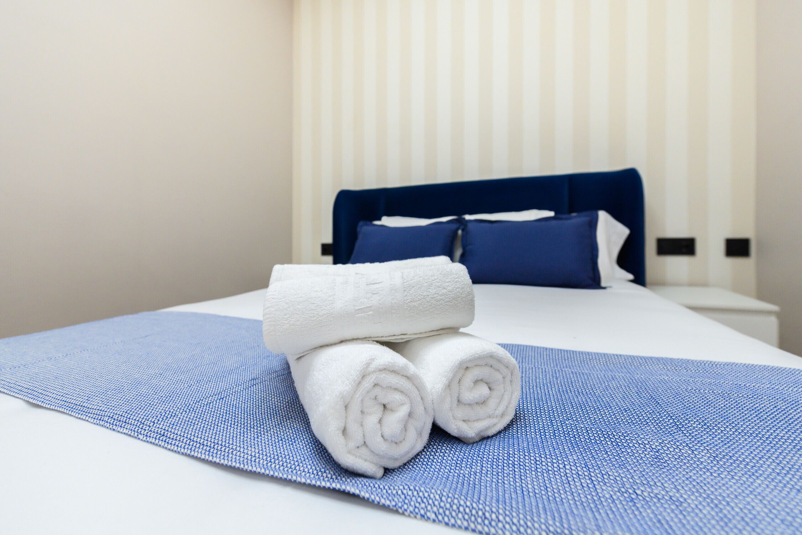 Una cama bien hecha con ropa de cama azul y toallas blancas.