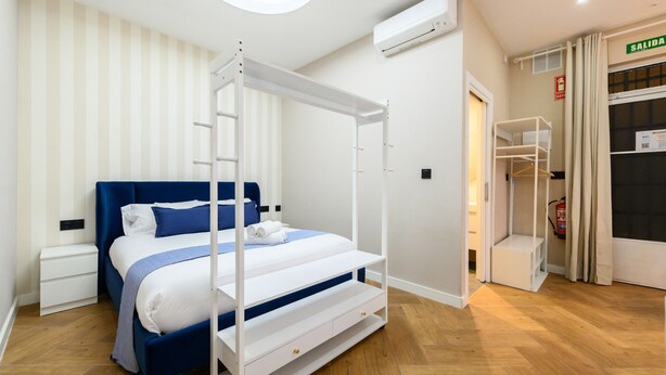 A bedroom with a four-poster bed, a white nightstand, a wardrobe, and a ceiling-mounted air conditioner. - M Nda11bii Acogedor Estudio Interior con Todas la (Madrid)