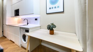 A compact kitchen with a washing machine, a microwave, and a small table with a potted plant. - M Nda11bii Acogedor Estudio Interior con Todas la (Madrid)
