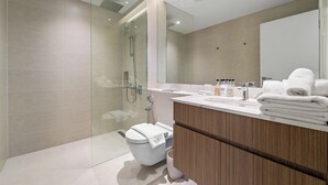 Ein modernes Badezimmer mit einer einteiligen Duschkabine, einer weißen Toilette und einem Waschtisch mit Spiegel.