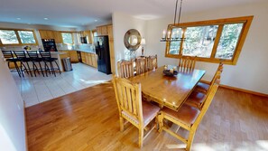 Une cuisine spacieuse avec des meubles en bois, un coin repas doté d’une grande table et de chaises en bois, et une vue sur l’extérieur par une fenêtre.