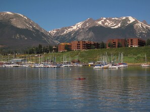 A marina with boats, a person in a kayak, and mountains in the background. - Pet Friendly, Private Hot Tub! Great for Gatherings, Teams. 2 Living Areas! (Silverthorne)