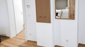 Een moderne hotelkamer met een houten vloer, witte muren en een grote spiegel.