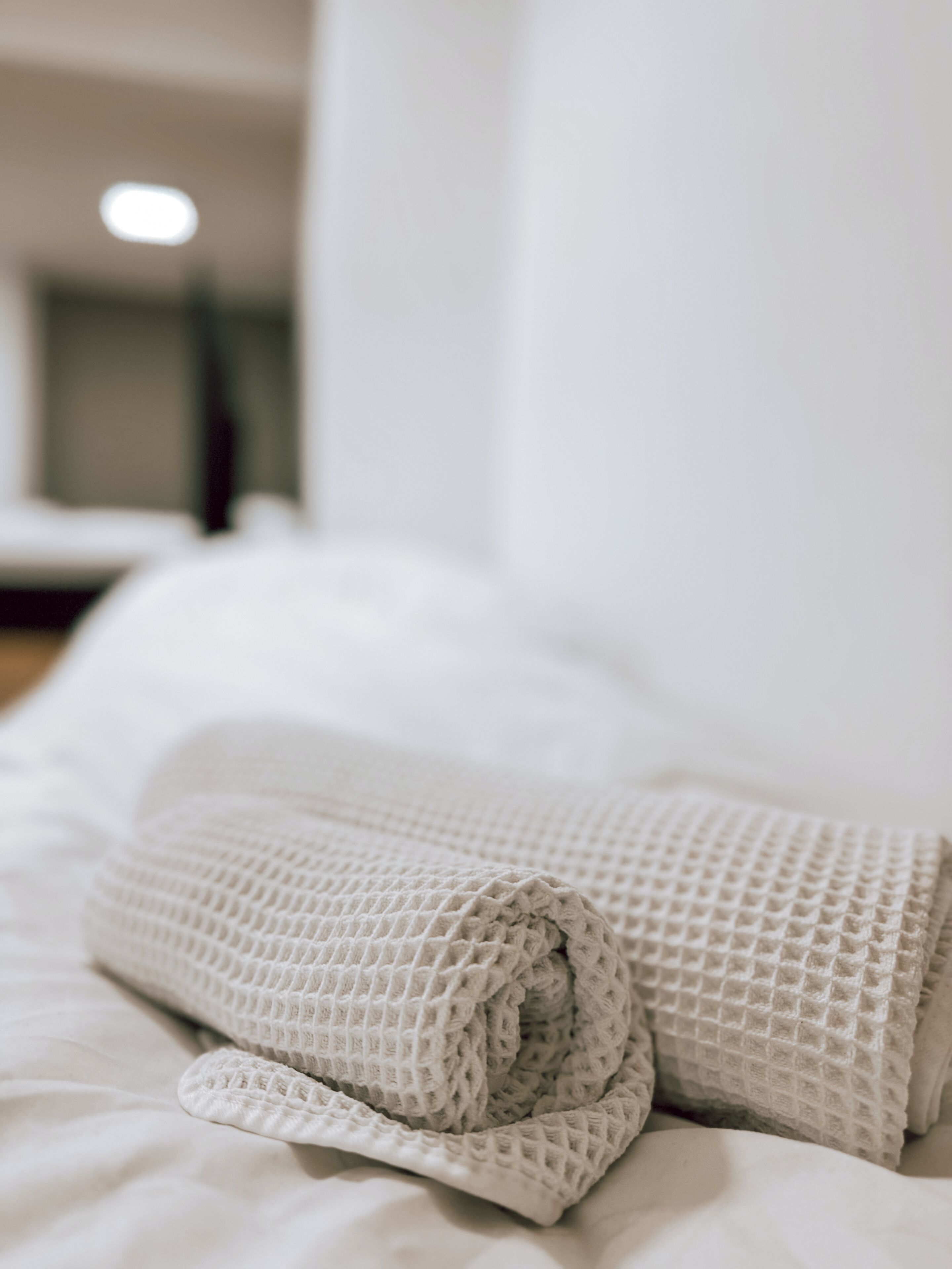 A neatly made bed with a textured blanket and pillows.