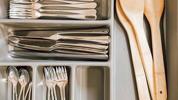 Uma gaveta de cozinha com utensílios organizados em divisórias.