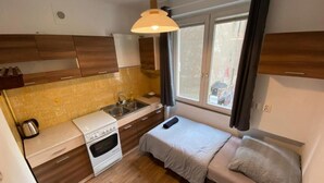A compact kitchenette with a stove, sink, and a small dining table. - Fantastic Inn Warsaw - CH10 (Warsaw)