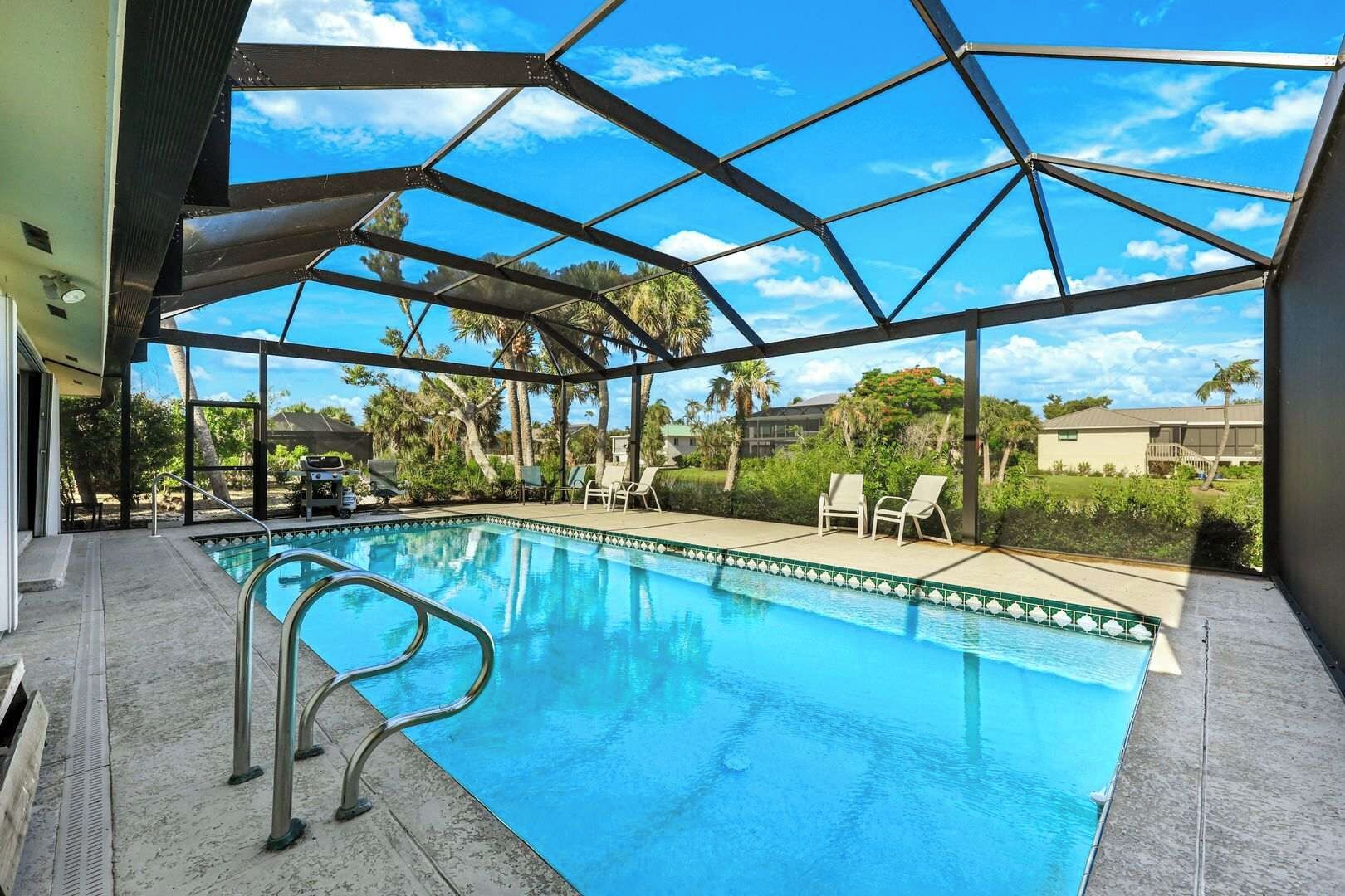 Ein Schwimmbecken mit Glasüberdachung, umgeben von Liegestühlen und Palmen.