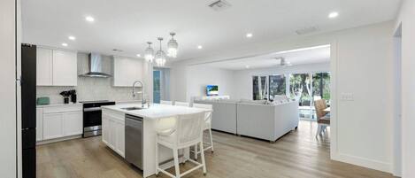 A modern kitchen with white cabinetry, a central island, and pendant lighting.